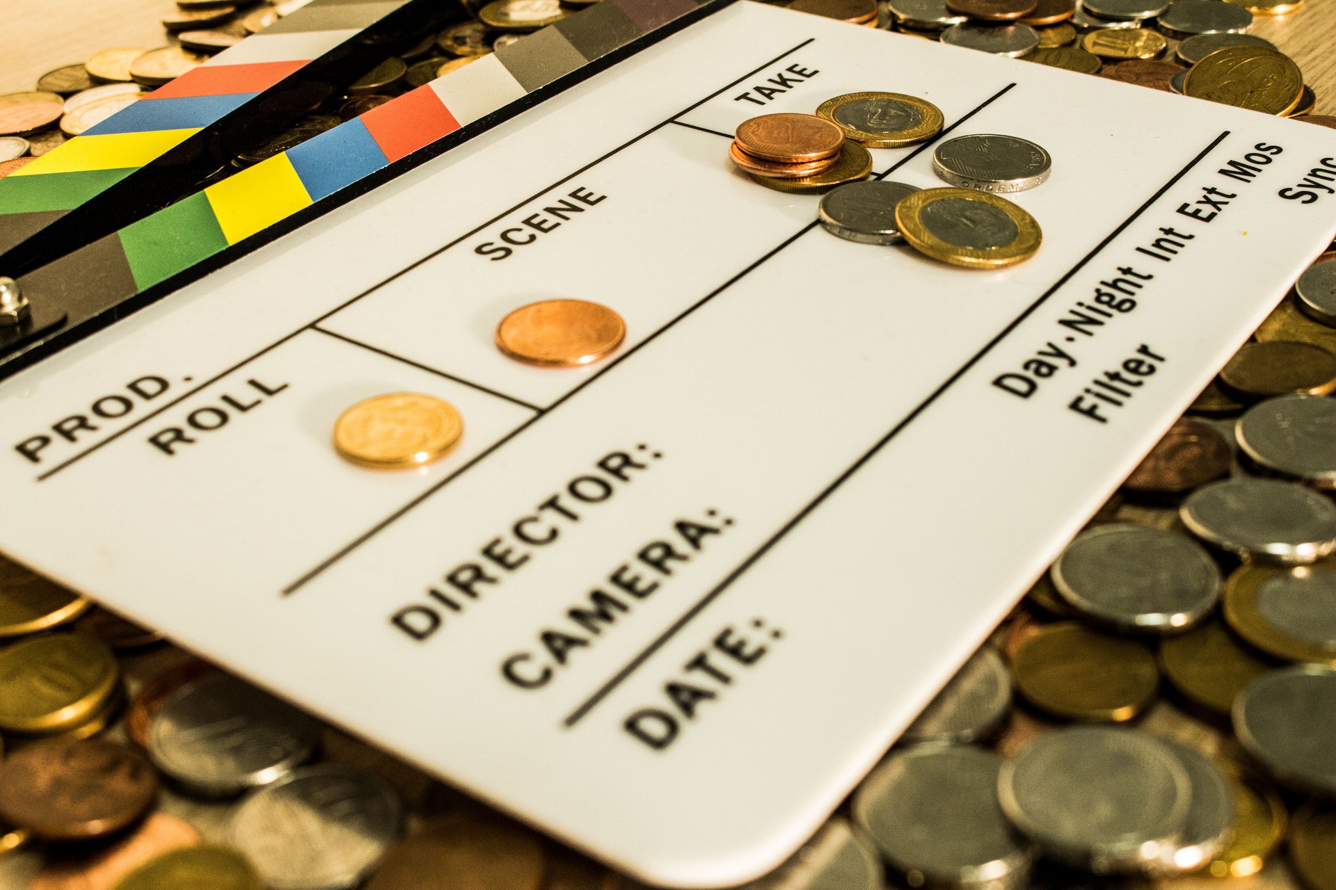 Clapperboard with coins above and on it creating a relation between filmmaking and business